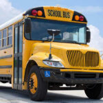 LEAKED Docs: School Buses Spy on Drivers! Yellow school bus on road under cloudy sky.