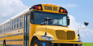 Yellow school bus on road under cloudy sky.