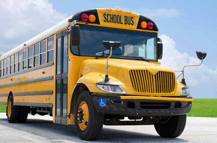 271198973 Yellow school bus on road under cloudy sky.