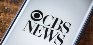 Phone screen showing CBS News logo.