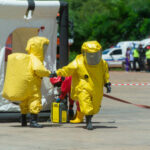 Hazmat-suited workers exit a decontamination tent