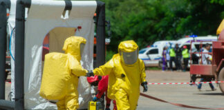 Hazmat-suited workers exit a decontamination tent
