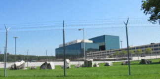 Chain-link fence in front of a large modern office complex