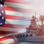 US flag and navy warship in the background.