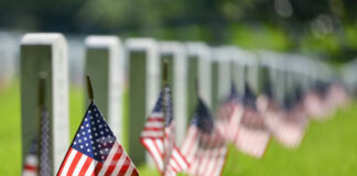 American flags beside gravestones in a cemetery.