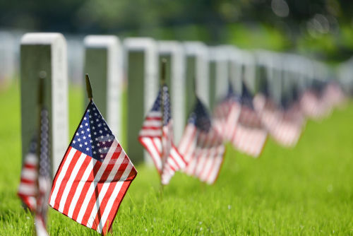 shutterstock_1041465589 American flags beside gravestones in a cemetery.