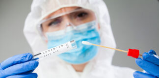 Healthcare worker holding a COVID-19 test kit and swab