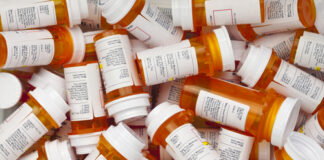 A pile of prescription medication bottles with labels