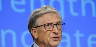 A man in a suit speaking at a conference with a blue background