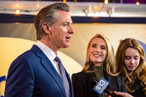 Sacramento,,Ca,,U.s.a.,-,Feb.,6,,2024:,Governor,Gavin,Newsom A man in a suit speaking at an event with two women nearby, one smiling and the other holding a microphone