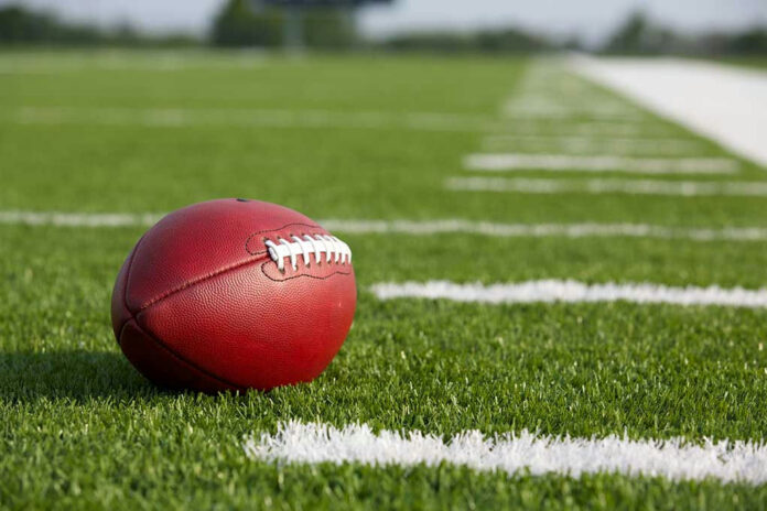 160264247 Football resting on a grassy field.