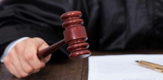 Judge striking gavel near documents and pen.