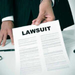 Holding a document titled Lawsuit in an office.