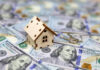 Mini house on top of hundred-dollar bills.