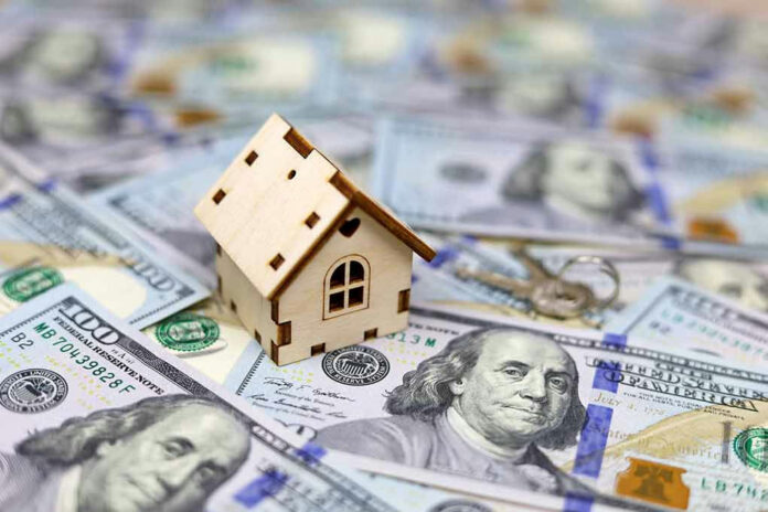 Mini house on top of hundred-dollar bills.