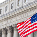 Trump Tariffs Survive Court Challenge For Now United States courthouse with American flag waving.
