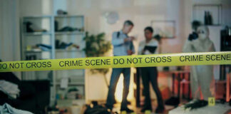 Crime scene tape in front of investigators and forensic unit.
