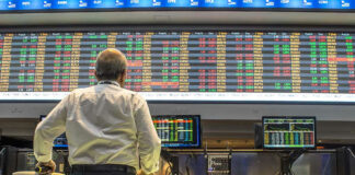 Person viewing stock market data on multiple screens.