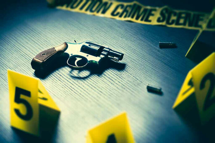 A revolver on a table surrounded by evidence markers and caution tape