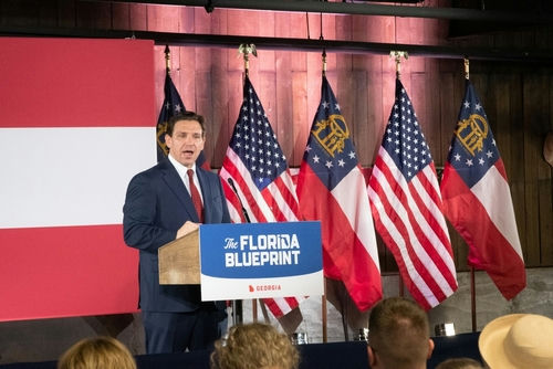 shutterstock2282918981-1jpg Man speaking at The Florida Blueprint event with flags.