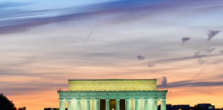 Lincoln Memorial illuminated at sunset with reflection in water