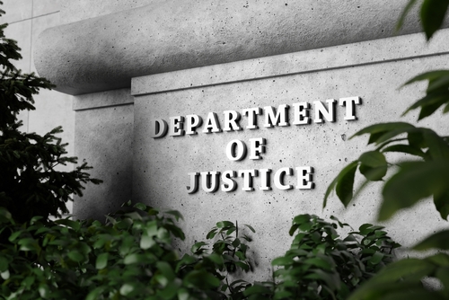 Sign for the Department of Justice surrounded by greenery