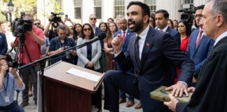 A speaker at a podium passionately addressing a crowd, wearing rainbow socks
