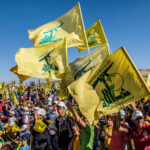 People waving Hezbollah flags at a large outdoor gathering.