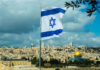 Israeli flag waving in front of the Jerusalem skyline with a golden dome in view