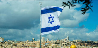 Israeli flag waving in front of the Jerusalem skyline with a golden dome in view
