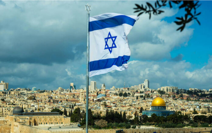 1065289910 Israeli flag waving in front of the Jerusalem skyline with a golden dome in view