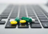 Pills scattered on a laptop keyboard.
