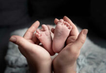 Mile 113 Miracle Stuns Jersey Hands holding newborn babys feet.