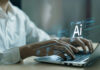 Hands typing on laptop with AI holograms.