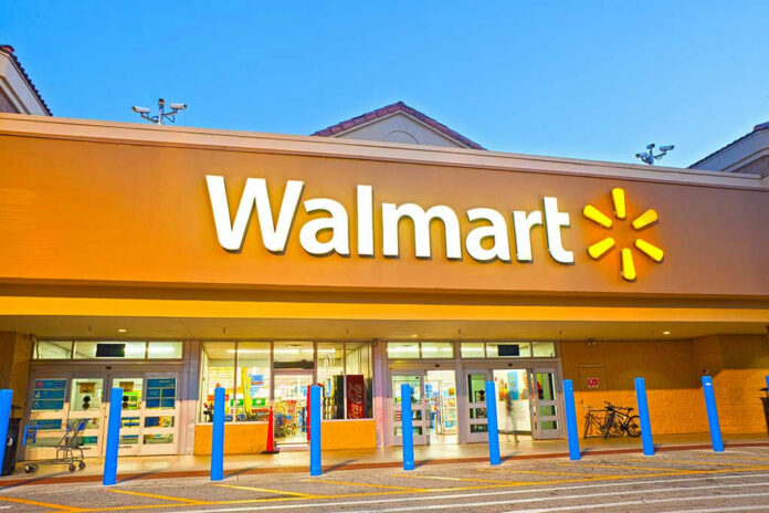 Walmart store entrance with blue bollards at dusk.