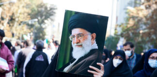 Person holding a large portrait in a crowd