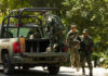 Soldiers loading equipment into a military vehicle in forest.