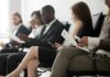 Job applicants seated in a waiting area reviewing documents
