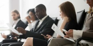 Job applicants seated in a waiting area reviewing documents