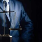 Should Non-Killers Face Life For Murder? Scales of justice held by a person in a suit