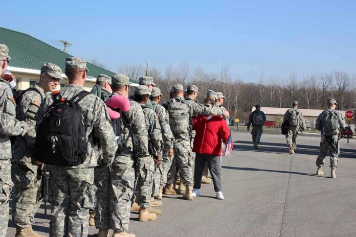 Soldiers in uniform line up outdoors with gear