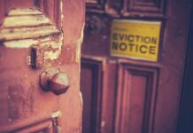 Outrage in Baltimore: Pay-To-Get Home Back Weathered wooden door with eviction notice