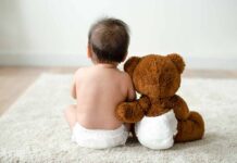 Luxury Parenting Team—Middle Class Gutted Baby in diaper sitting with teddy bear