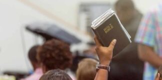 Hand holding a Bible in a crowded church service