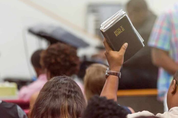 Hand holding a Bible in a crowded church service