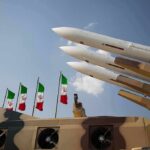 Airport Hit, Allies FUME — Tehran Miscalculated Missile launchers on a military vehicle with flags in the background