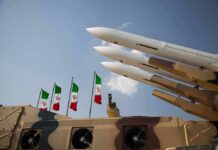 Airport Hit, Allies FUME — Tehran Miscalculated Missile launchers on a military vehicle with flags in the background