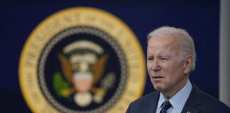 A man speaking in front of presidential seal.