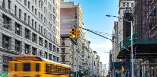 City street with yellow school bus passing under traffic light