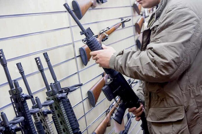 shutterstock_1181974606 Person examining a black rifle in a gun store